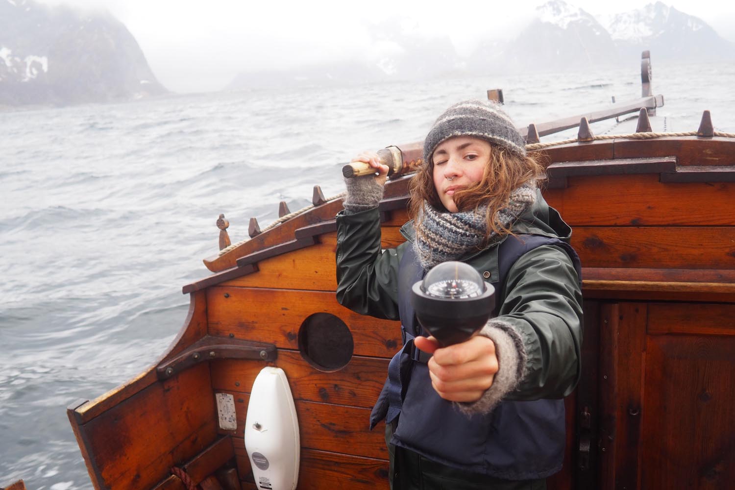Navigasjon-krysspeiling-seiltur Ei jente styrer trebaten mens hun tar krysspeiling med kompass for a navigere